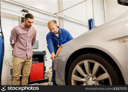auto service, repair, maintenance and people concept - mechanic with clipboard pointing at bumper and man or owner at car shop