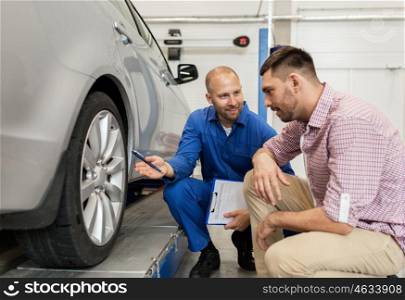 auto service, repair, maintenance and people concept - mechanic with clipboard showing tire to man or owner at car shop