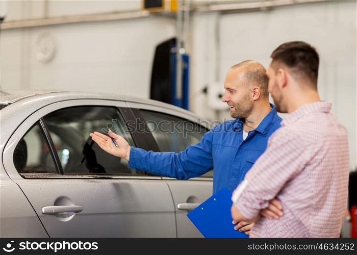 auto service, repair, maintenance and people concept - mechanic with clipboard showing side window to man or owner at car shop