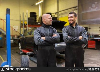 auto service, repair, maintenance and people concept - mechanics or tire changers at car shop. auto mechanics or tire changers at car shop