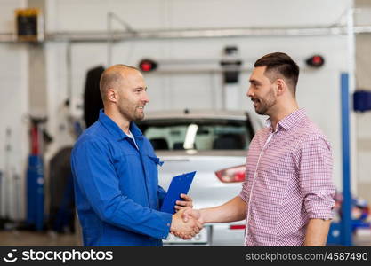 auto service, repair, maintenance, gesture and people concept - mechanic with clipboard and man or owner shaking hands at car shop