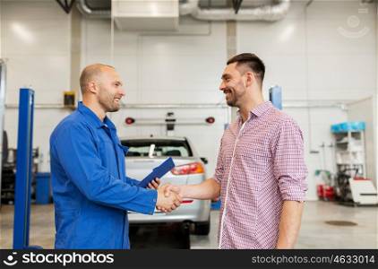 auto service, repair, maintenance, gesture and people concept - mechanic with clipboard and man or owner shaking hands at car shop
