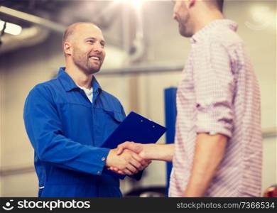 auto service, repair, maintenance, gesture and people concept - mechanic with clipboard and man or owner shaking hands at car shop. auto mechanic and man shaking hands at car shop