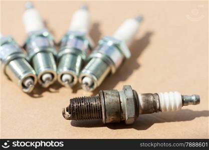 Auto service. Set of car spark plugs as spare part of auto transportation on brown.