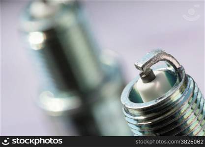 Auto service. Two new car spark plugs as spare part of auto transportation on gray background.