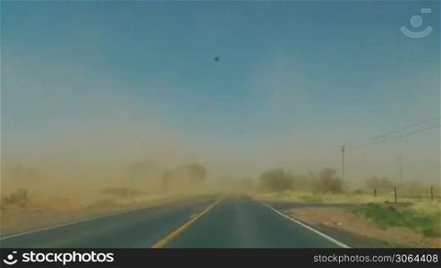 Autofahrt auf dem Highway durch die Wuste im Sandsturm