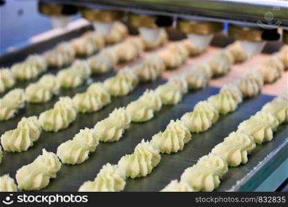 Automated biscuit cookies production process. Conveyor transfers the biscuits from the forming machine to the oven band.Selective focus.