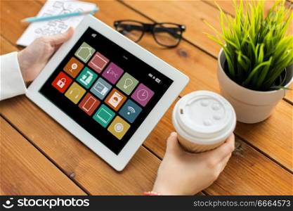 automation, internet of things and technology concept - close up of female hands with smart home icons on tablet pc computer screen and coffee on wooden table background. hands with smart home icons on tablet computer