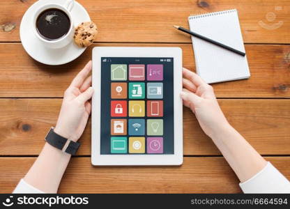 automation, internet of things and technology concept - close up of female hands with smart home icons on tablet pc computer screen and coffee on wooden table background. hands with smart home icons on tablet computer