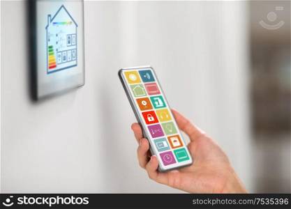 automation, internet of things and technology concept - hand with smart home menu icons on smartphone screen. hand with smart home icons on smartphone screen
