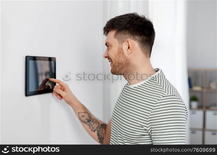 automation, internet of things and technology concept - happy smiling man using tablet pc computer at smart home. smiling man using tablet computer at smart home