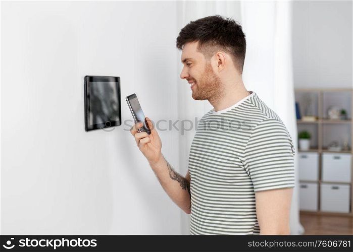 automation, internet of things and technology concept - happy smiling man with smartphone using tablet pc computer at smart home. smiling man using tablet computer at smart home