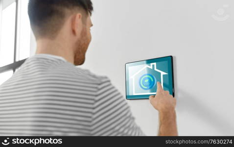 automation, internet of things and technology concept - man looking at tablet pc computer at smart home. man looking at tablet computer at smart home