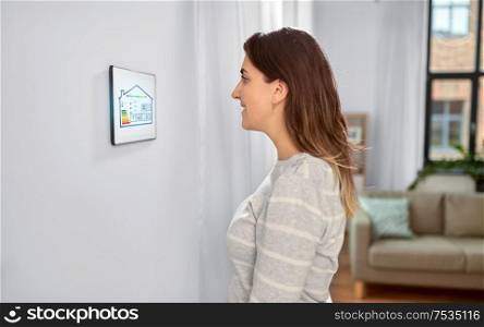 automation, internet of things and technology concept - woman looking at tablet pc computer with energy saving options at smart home. woman looking at tablet computer at smart home