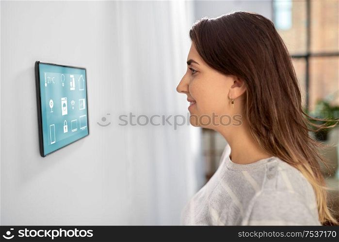 automation, internet of things and technology concept - woman looking at tablet pc computer at smart home. woman looking at tablet computer at smart home
