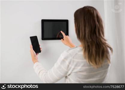 automation, internet of things and technology concept - woman using tablet pc computer and smartphone at smart home. woman using tablet computer and smartphone