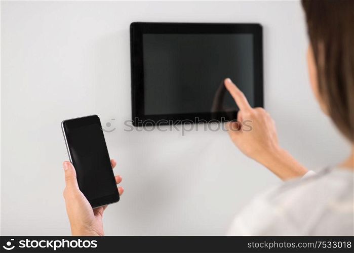 automation, internet of things and technology concept - woman using tablet pc computer and smartphone at smart home. woman using tablet computer and smartphone