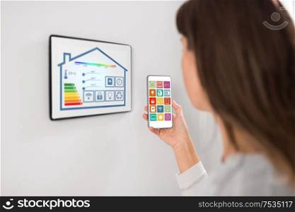 automation, internet of things and technology concept - woman using tablet pc computer and smartphone with menu icons on screen at smart home. woman using tablet pc and smartphone at smart home