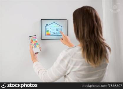 automation, internet of things and technology concept - woman using tablet pc computer and smartphone with energy saving options at smart home. woman using tablet computer and smartphone