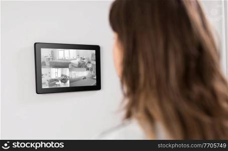 automation, security and technology concept - woman having video surveillance on tablet pc computer at smart home. woman having video control from tablet pc at home