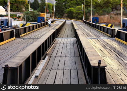 Automobile and pedestrian bridge over the Corinth Canal in Greece in the soft rays of morning light. The bridge is flooded when ships and boats pass through the canal, an image with copy space.. View of the submersible bridge over the Corinth Canal, on which the motorcycle rides, close-up.