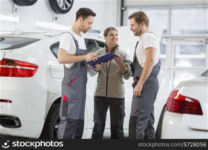 Automobile mechanics discussing over clipboard in car repair shop