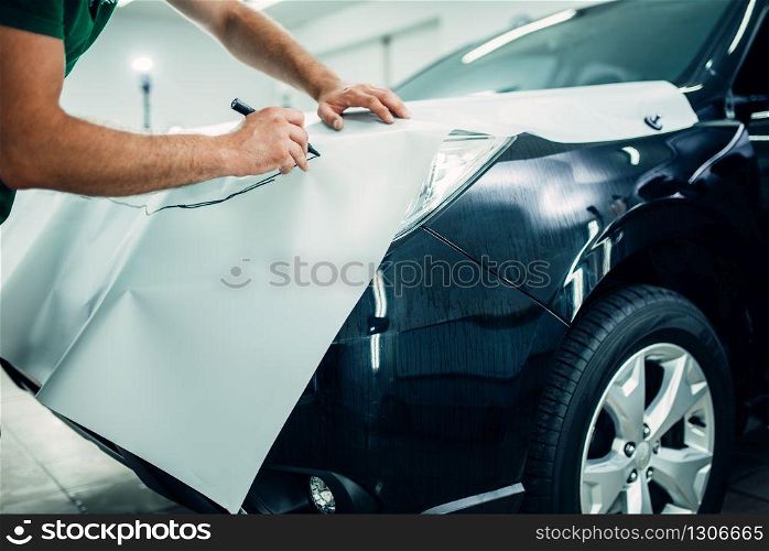 Automobile paint protection film installation process. Worker hands prepares protect coating against chips and scratches