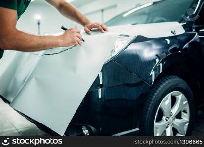 Automobile paint protection film installation process. Worker hands prepares protect coating against chips and scratches