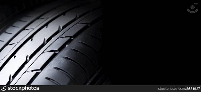 Automobile tire tread with a depth and light in the darkness , selective focus and panoramic banner copy space on black background
