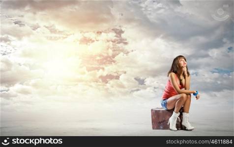 Autostop traveling. Young pretty girl traveler sitting on suitcase
