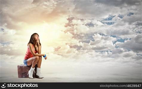 Autostop traveling. Young pretty girl traveler sitting on suitcase