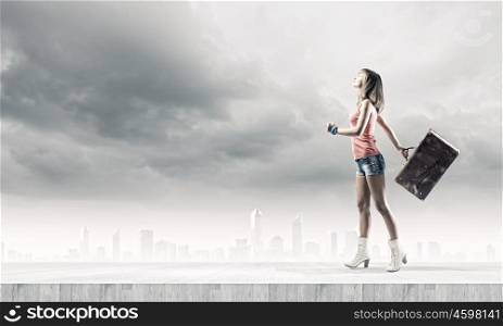 Autostop traveling. Young pretty woman tourist walking with suitcase