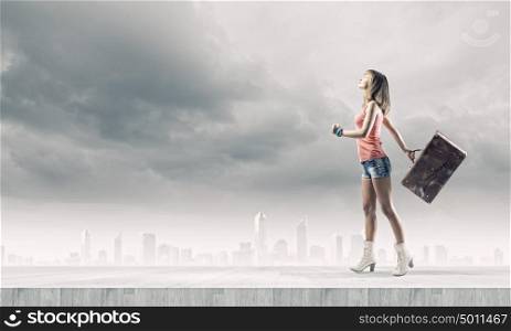 Autostop traveling. Young pretty woman tourist walking with suitcase