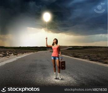 Autostop traveling. Young pretty woman tourist with suitcase walking on road