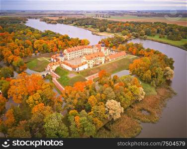 Autumn aerial view of Medieval castle in Nesvizh. Colorful maple park in Niasvizh ancient town. Minsk Region, Belarus
