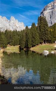 Autumn alpine Dolomites mountain and lake scene, Sudtirol, Italy. Peaceful view near Sella Pass. Picturesque traveling, seasonal, nature and countryside beauty concept scene.