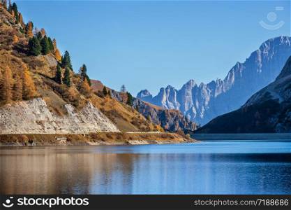 Autumn alpine Fedaia mountain Lake and Pass, Trentino, Dolomites Alps, Italy. Picturesque traveling, seasonal and nature beauty concept scene.