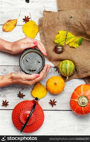Autumn and tea. Cup of tea in hand and the autumn decoration with pumpkins