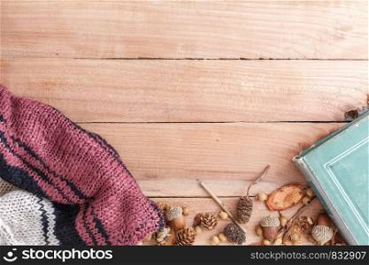autumn background. cones,acorns and pieces of wood with a warm jacket and an old book on a wooden background. the view from the top.