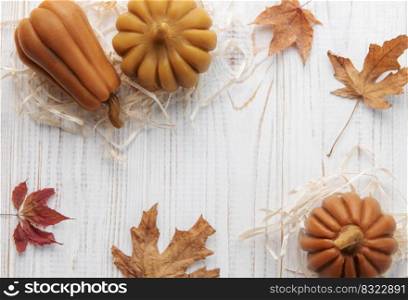 Autumn background. Frame of leaves and pumpkins on an aged white wooden background. Place for text.