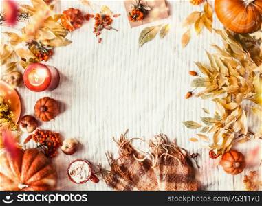 Autumn background make lake frame with yellow fall leaves, pumpkins, scarf, cappuccino, burning candles, apples and rowan. Top view. Cozy autumnal layout with copy space. Seasonal arrangement