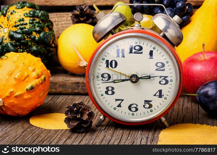 Autumn background with clock,pumpkin, apples and grapes.Autumnal concept.Harvesting. Beautiful autumn harvest and clock