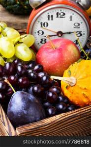 Autumn background with clock,pumpkin, apples and grapes.Autumnal concept.Harvesting. Beautiful autumn harvest and clock