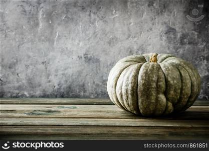 Autumn background with pumpkin on wooden tabel against old rust condition vintage wall, space for text