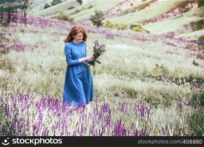 autumn - beautiful girl on a meadow with a bouquet of wildflowers