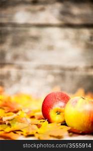 Autumn border from apples and maple leaves on old wooden background
