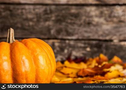 Autumn border from pumpkin and maple leaves on wooden background