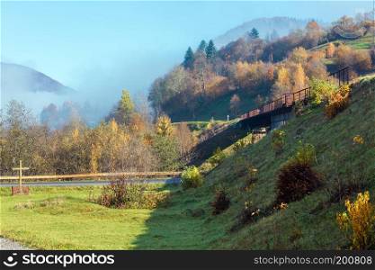 Autumn Carpathian Mountains misty landscape with  railroad bridge and village outskirts (Rakhiv district, Transcarpathia, Ukraine).
