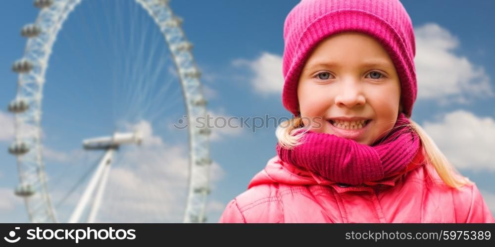 autumn, childhood, happiness and people concept - happy beautiful little girl portrait outdoors over london ferry wheel and blue sky background