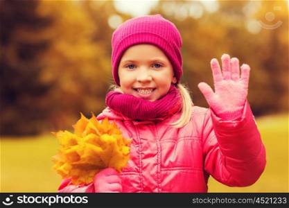 autumn, childhood, happiness and people concept - happy beautiful little girl with maple leaves bunch waving hand outdoors